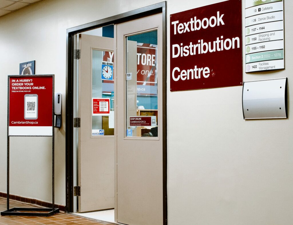 Entrance to Cambrian's Textbook Distribution Centre with signs and a door, located in a hallway.