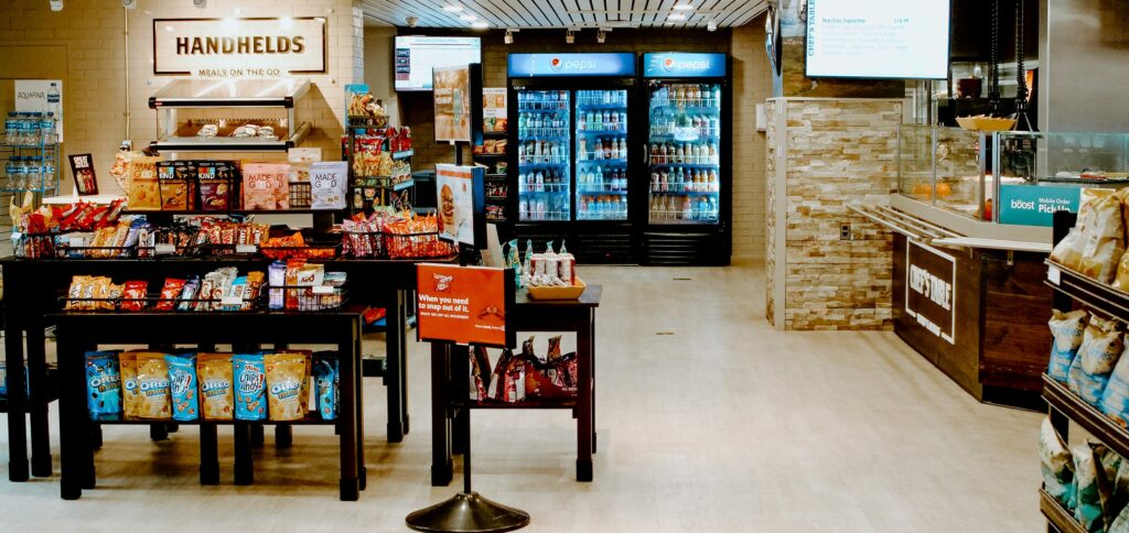 Convenience store interior, located within Cambrian's Cafeteria with snack shelves, drink coolers, and a deli counter.