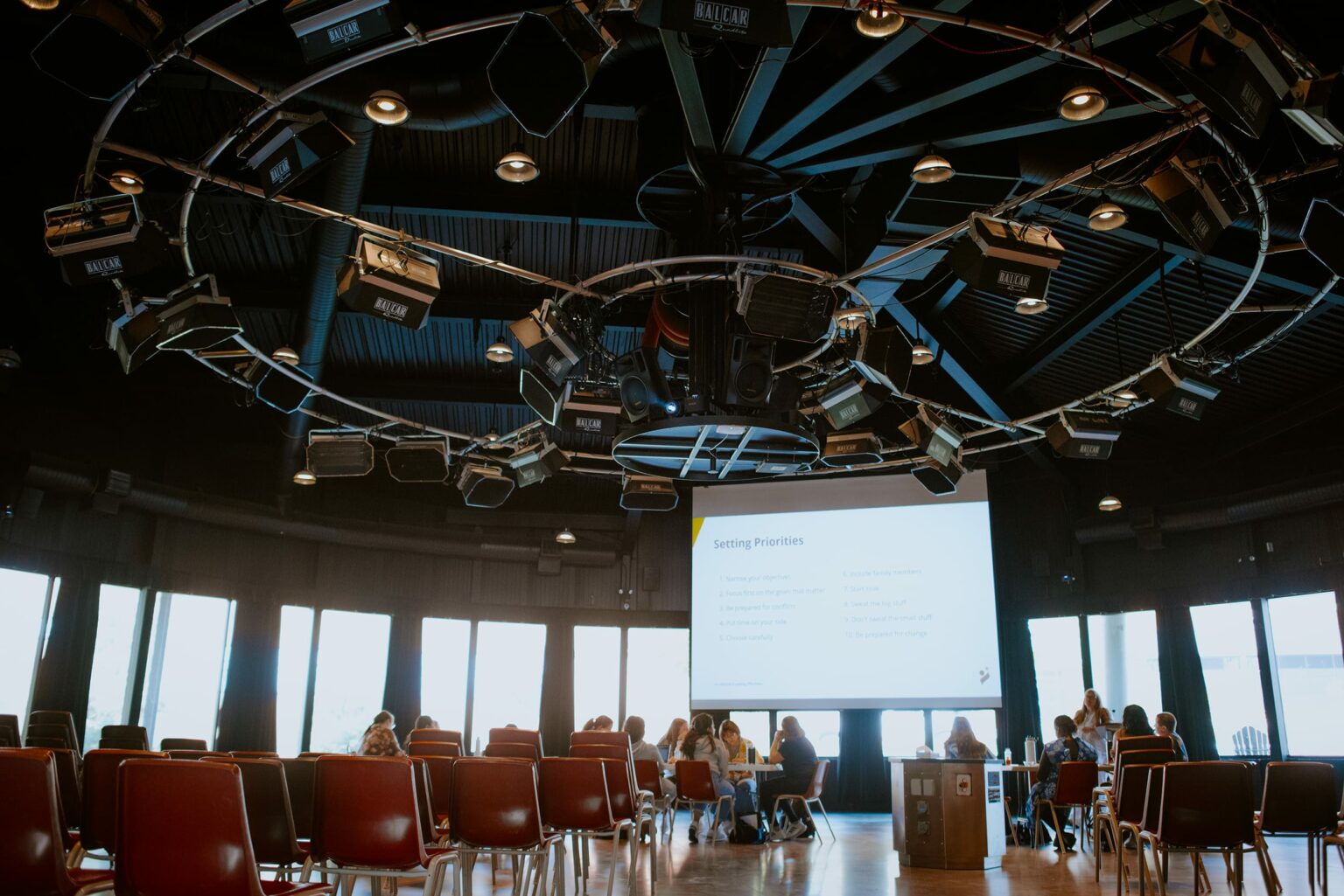A group of students seated inside Cambrian College's eDome facing a projector screen displaying a presentation titled "Setting Priorities.