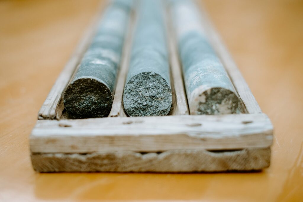 Close-up of rock core samples in a wooden tray, displayed in rows on a wooden surface.
