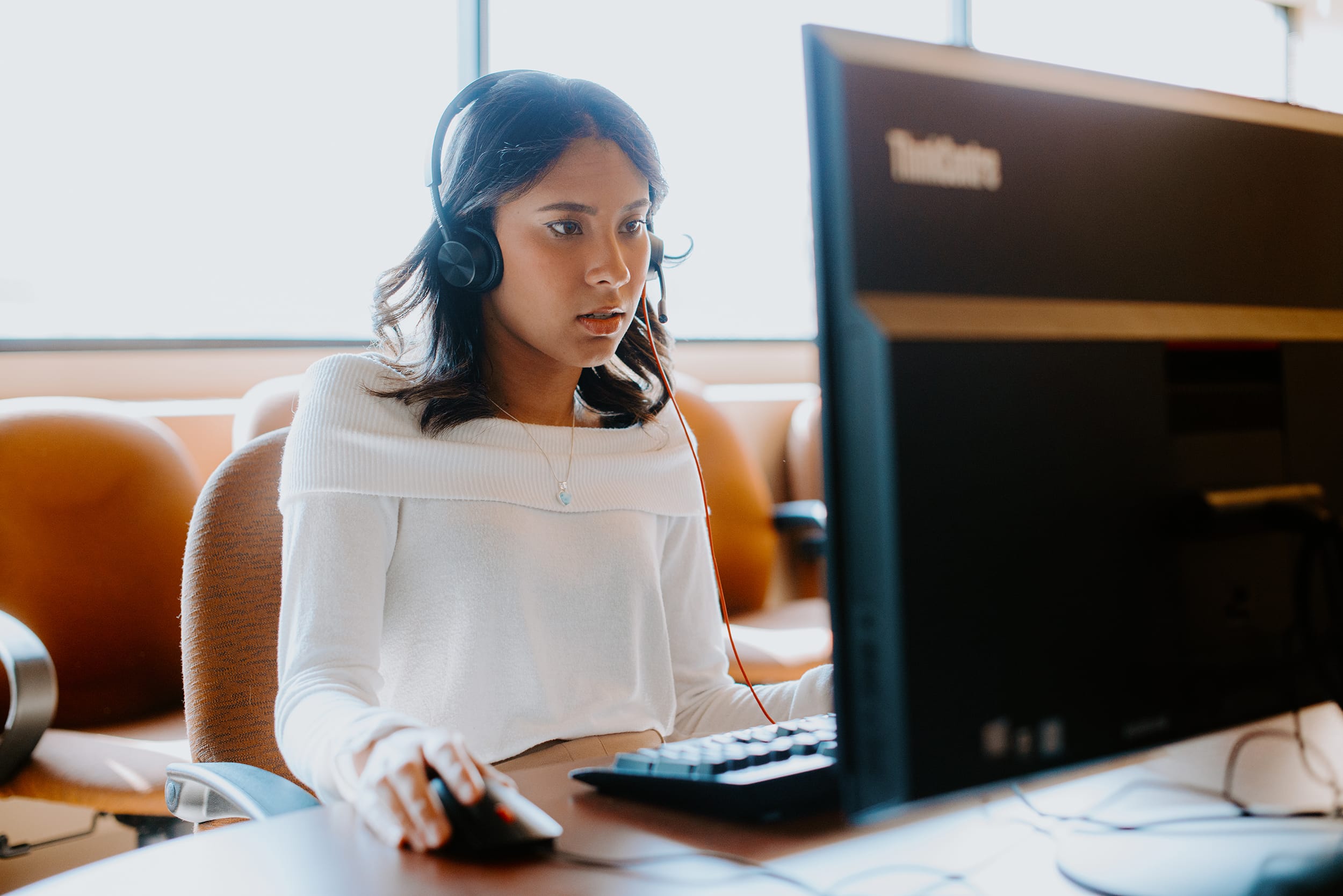 Student using a computer while wearing a headset in an office setting.