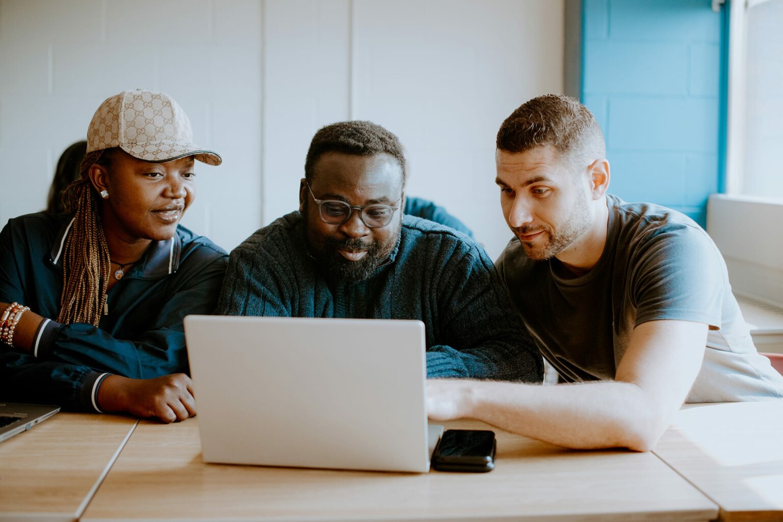 Three students sitting at a desk together with a computer