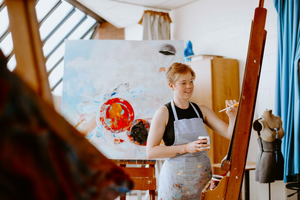 Artist painting on canvas in a studio with a mannequin nearby.