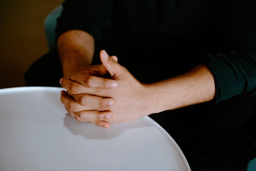 Student sitting at a round table with hands clasped.