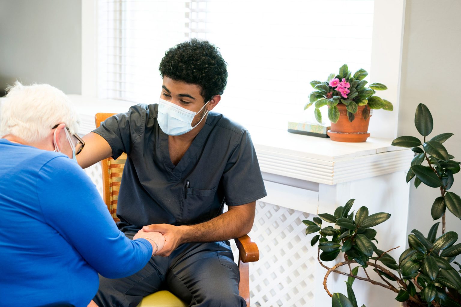 Health care worker with mask on helping elderly patient