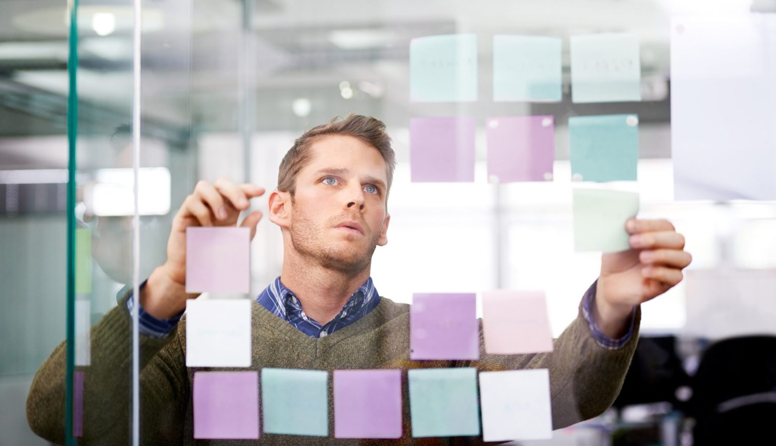 Man working on a whiteboard with sticky notes.