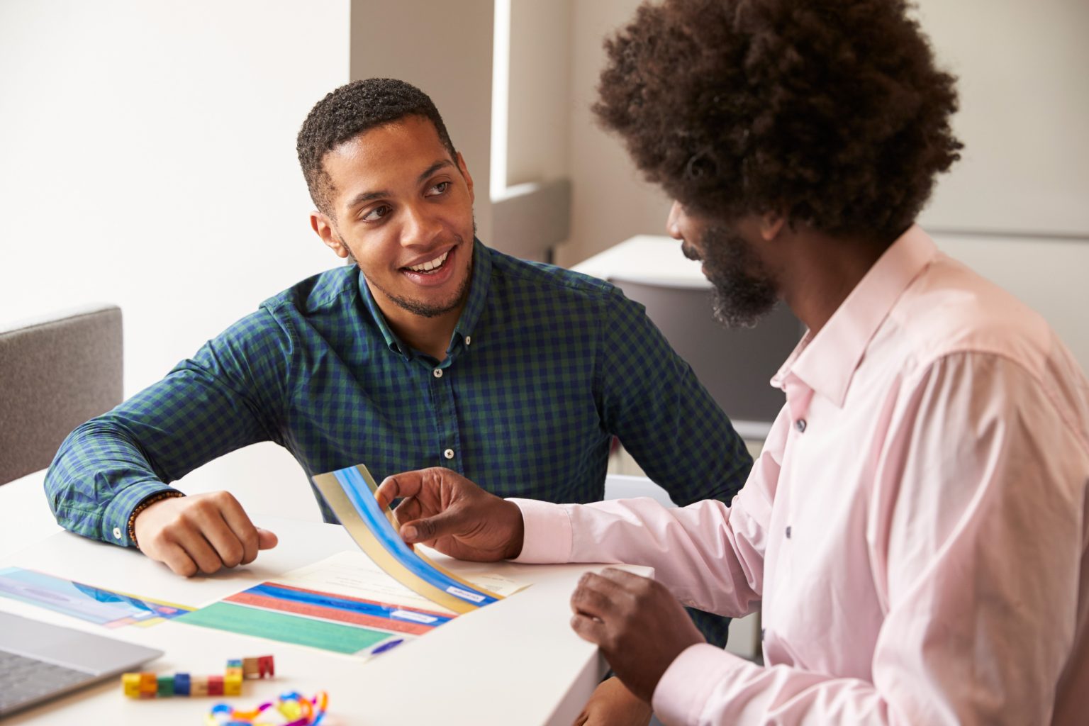 A male teacher working with a student at a desk.