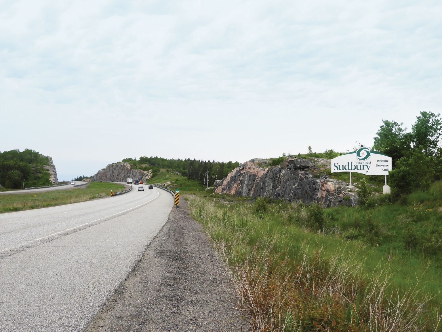 Picture of a Sudbury highway with a sign that reads 'welcome to Sudbury' in the background
