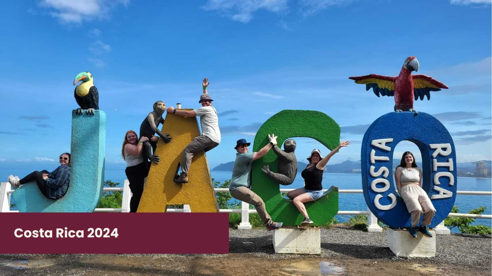 Six students pose on colorful "JACO COSTA RICA" letters topped with animal sculptures, set against a seaside background under a blue sky, capturing the spirit of Cambrian College Global Skills Opportunity.