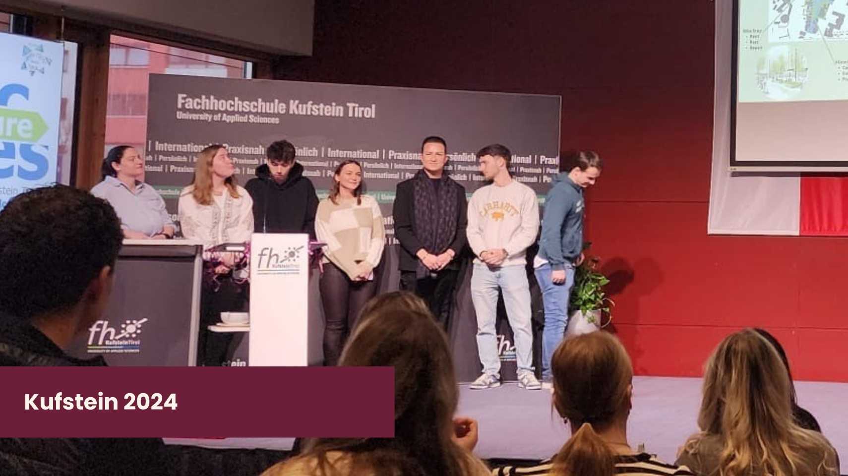 Seven students stand on stage at Fachhochschule Kufstein Tirol, presenting to an audience; a slide is projected on the wall and a sign reads "Kufstein 2024," showcasing their Cambrian College Global Skills Opportunity.