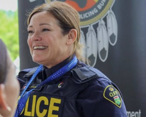 An OPP officer stands in front of a banner as part of a recruitment event.