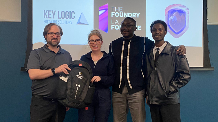 Three Cambrian College students and their professor pose for a photo at a recent hackathon in Sudbury where the students won the Best Use of UI/UX prize.
