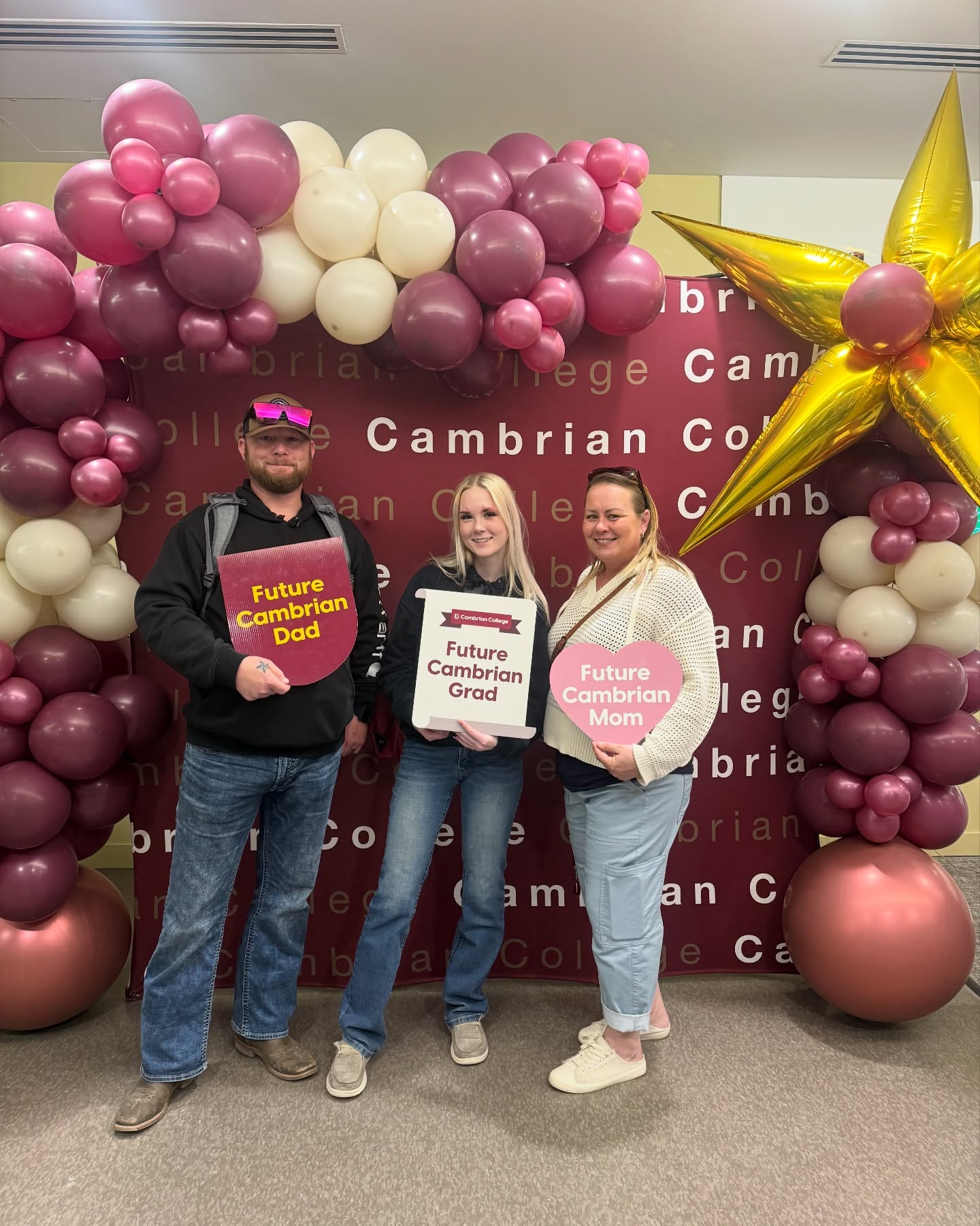 A future student and her parents stand in front of a Cambrian College banner at Open House